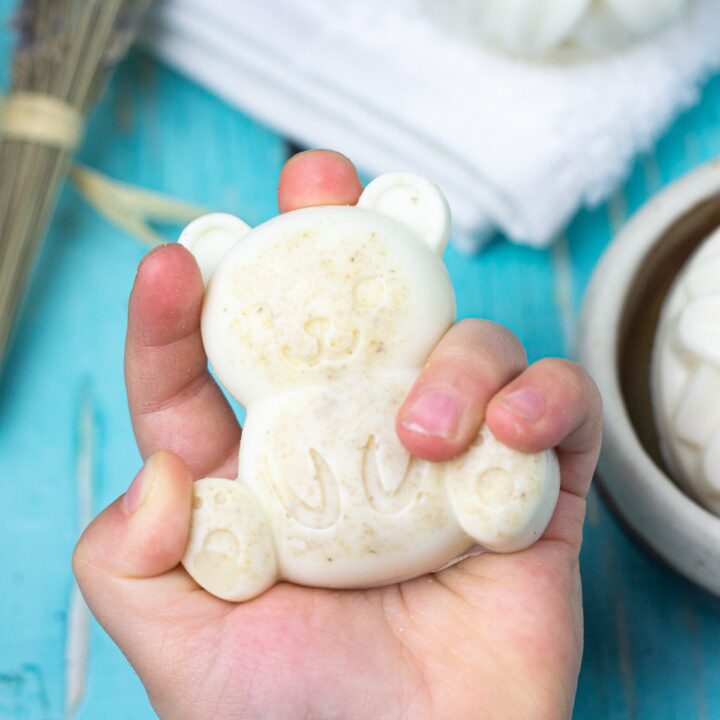 baby's hand holding teddy bear shaped brestmilk soap.