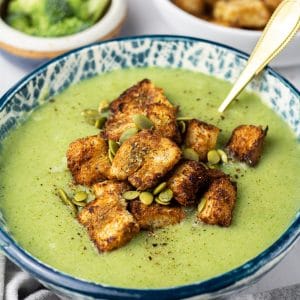 vegan cream of broccoli soup in bowl with croutons on top.