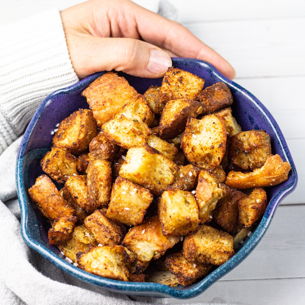 croutons in bowl with hand.