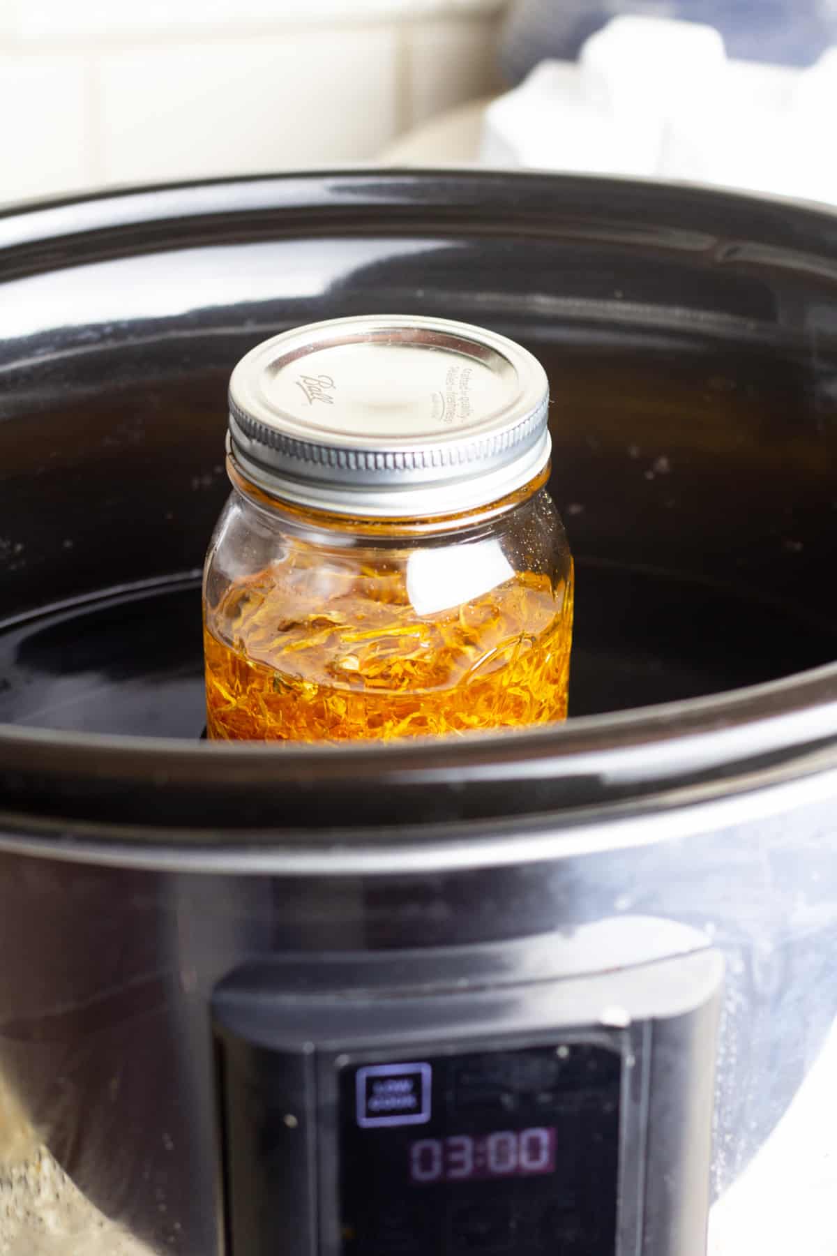 jar with calendula and oil in slow cooker.