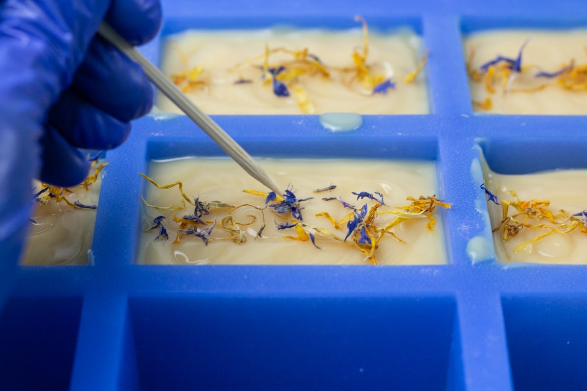 pressing flowers into soap with skewer.