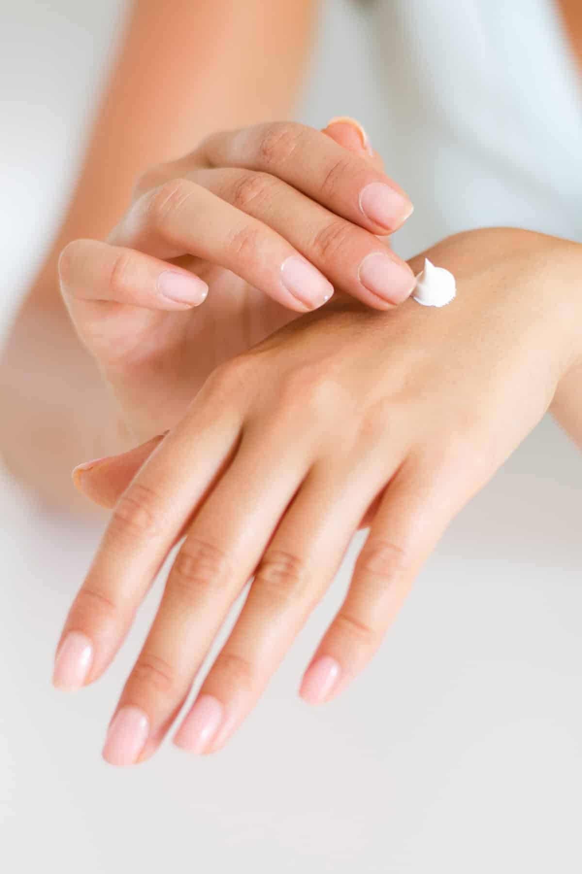 woman's hands applying lotion.