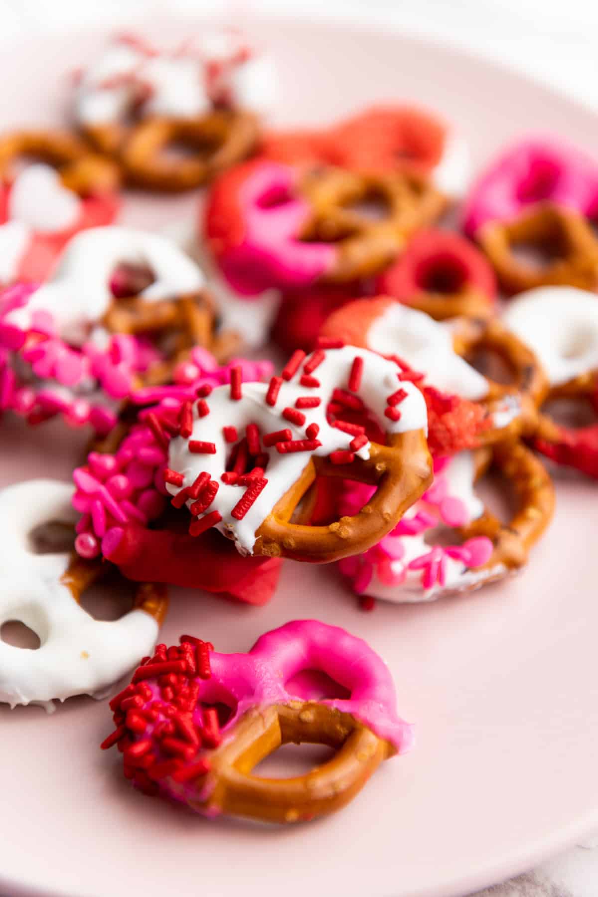 chocolate covered pretzels with pink and white chocolate and red sprinkles.