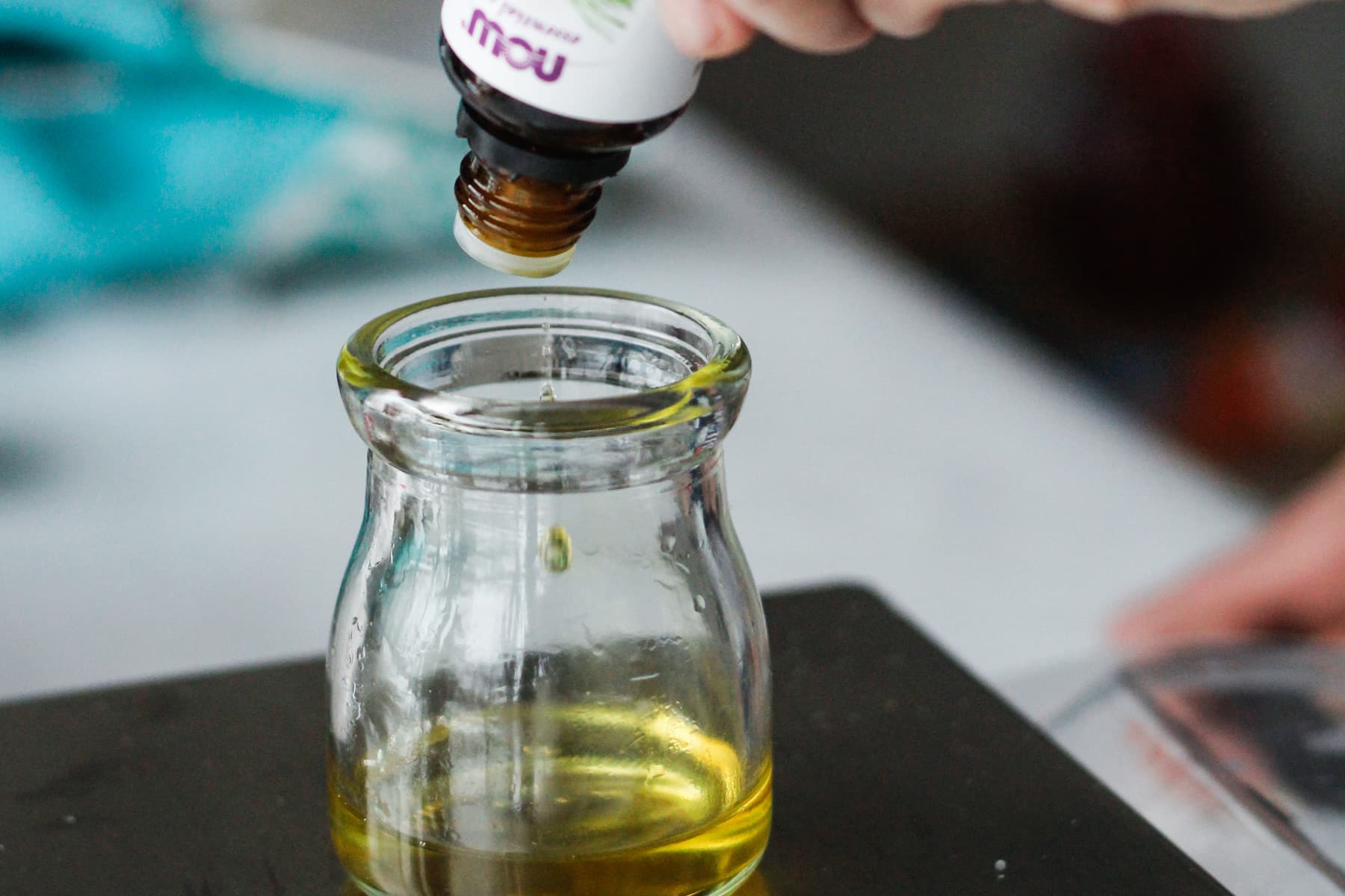 measuring essential oil into glass jar.