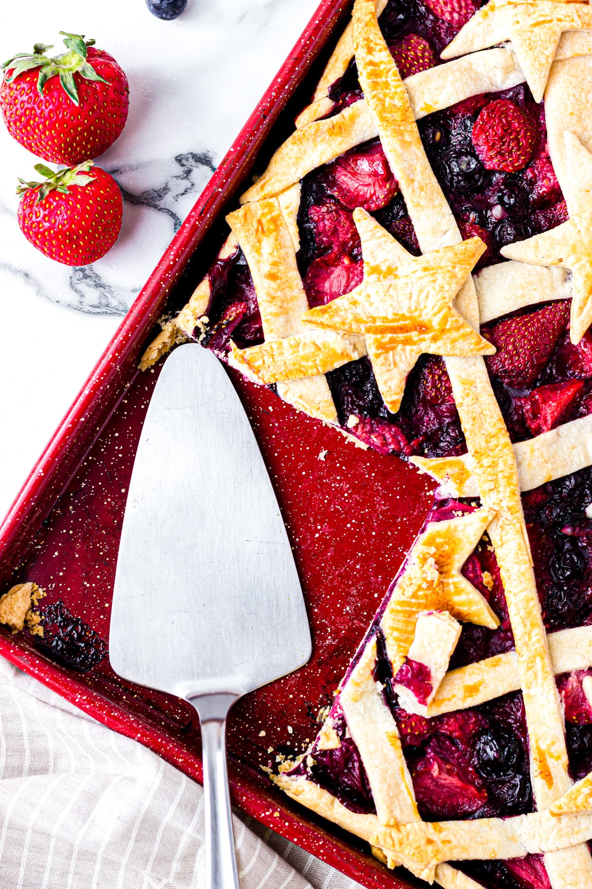 mixed berry slab pie on sheet with spoon.
