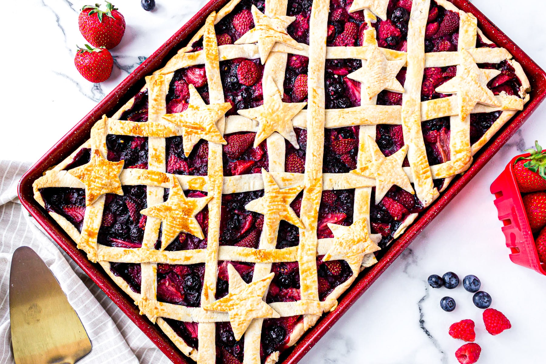 mixed berry slab pie on sheet decorated with stars.