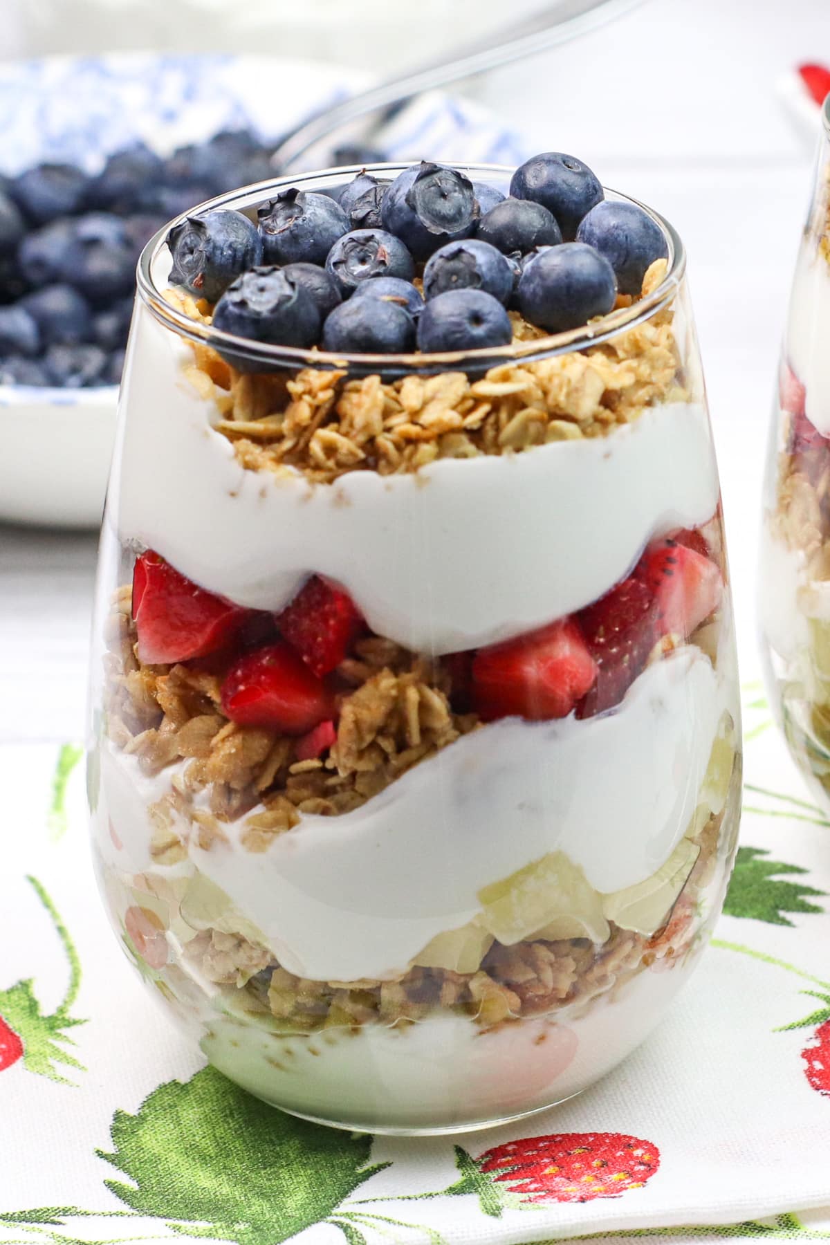 berries, granola and yogurt layered in glass cup.