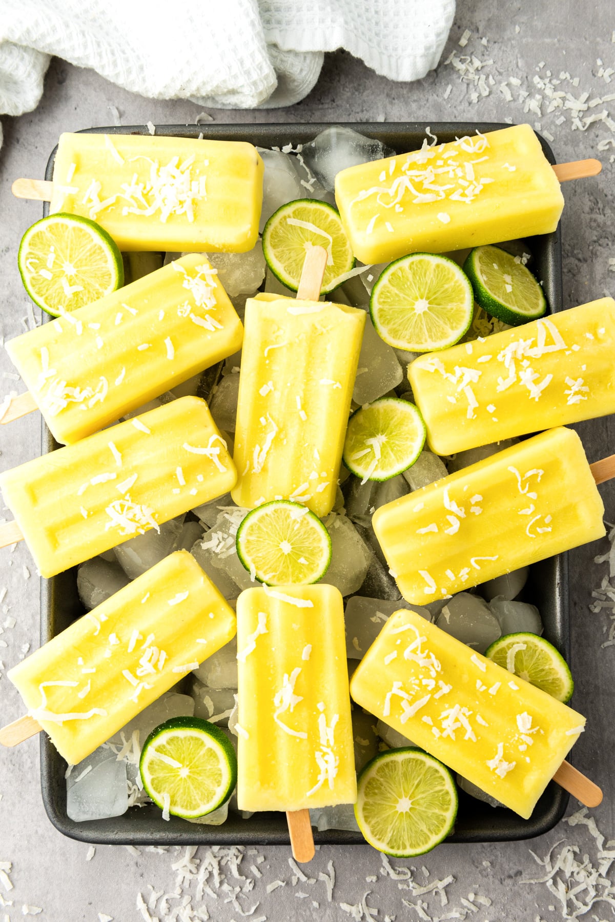pineapple popsicles on a tray with lime slices.