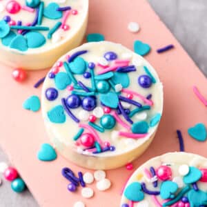 chcolate covered oreos with pink and blue sprinkles.