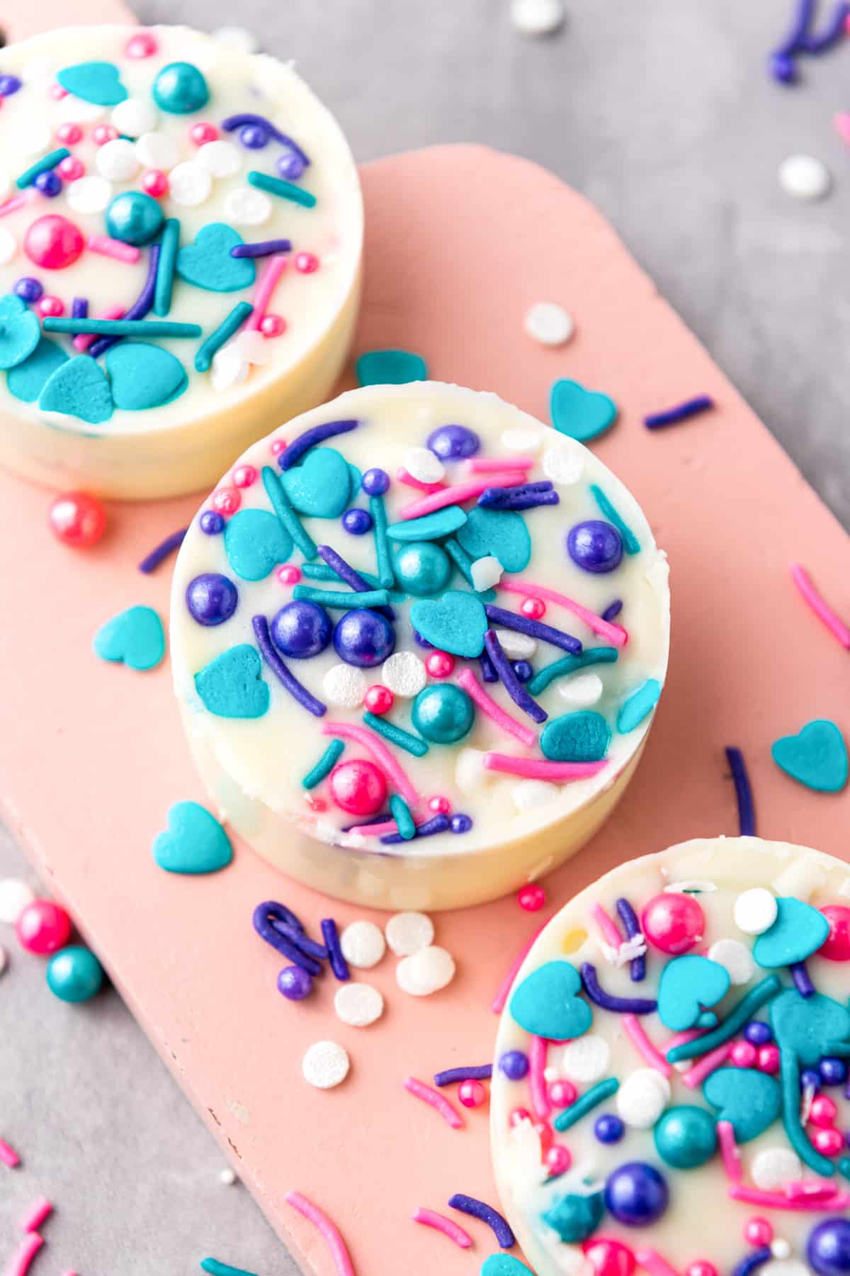 white chocolate-covered oreos with blue and pink sprinkles.